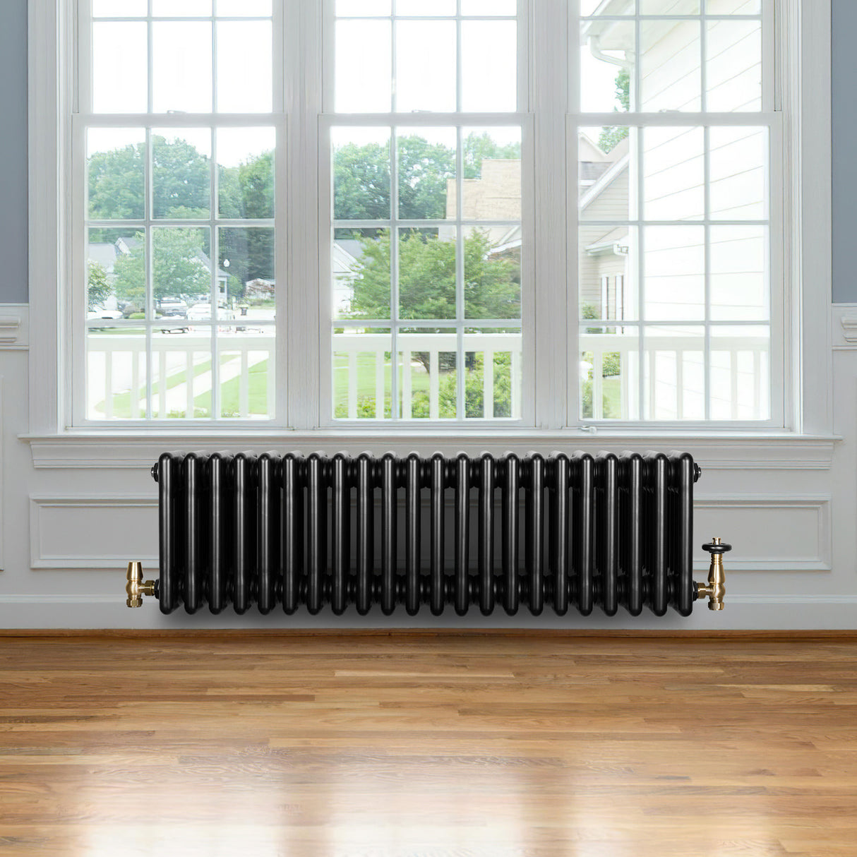 Radiatore tradizionale a 4 colonne, 300 x 1010 mm, finitura nera lucida, posizionato sotto una grande finestra in un ambiente luminoso