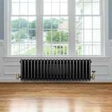 Radiatore tradizionale a 4 colonne, 300 x 1010 mm, finitura nera lucida, posizionato sotto una grande finestra in un ambiente luminoso