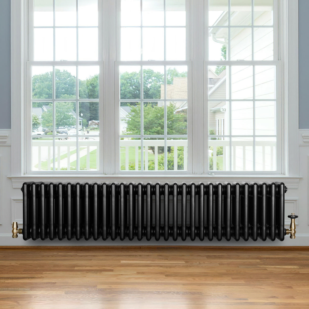 Radiatore tradizionale a 4 colonne, 300 x 1370 mm, finitura nera lucida, posizionato sotto una grande finestra con vista esterna