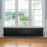 Radiatore tradizionale a 4 colonne, 300 x 1370 mm, finitura nera lucida, posizionato sotto una grande finestra con vista esterna