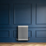 Radiatore tradizionale a 4 colonne, bianco, installato su una parete blu, con finitura liscia e dettagli eleganti in metallo