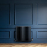 Radiatore tradizionale a 4 colonne in grigio antracite, installato su una parete blu scuro, con finitura liscia e dettagli metallici lucidi