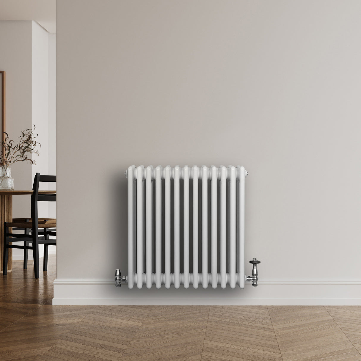 Radiatore tradizionale a 4 colonne, bianco lucido, con finiture cromate, installato su una parete in un ambiente moderno e luminoso