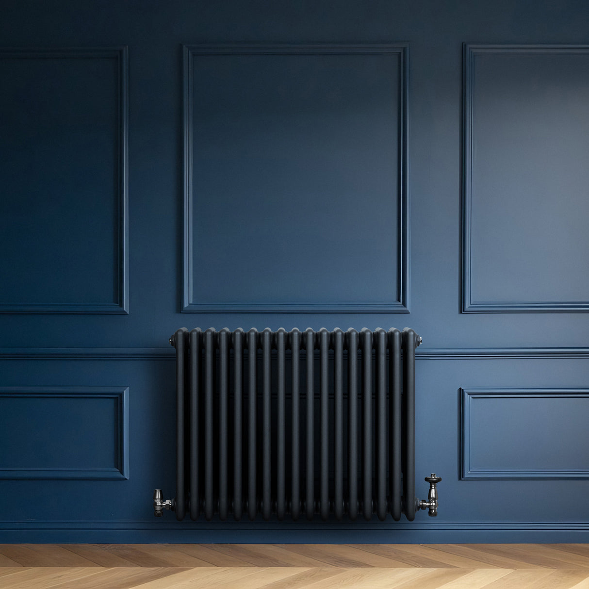 Radiatore tradizionale a 4 colonne orizzontali, grigio antracite, con finitura liscia, installato su parete blu scuro, elegante e moderno
