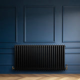 Radiatore tradizionale orizzontale a 4 colonne, colore nero, con finitura liscia, installato su parete blu scuro, elegante e moderno