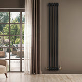 Radiatore tradizionale verticale a 4 colonne, finitura nera opaca, installato su parete beige, con valvola dorata e vista su giardino