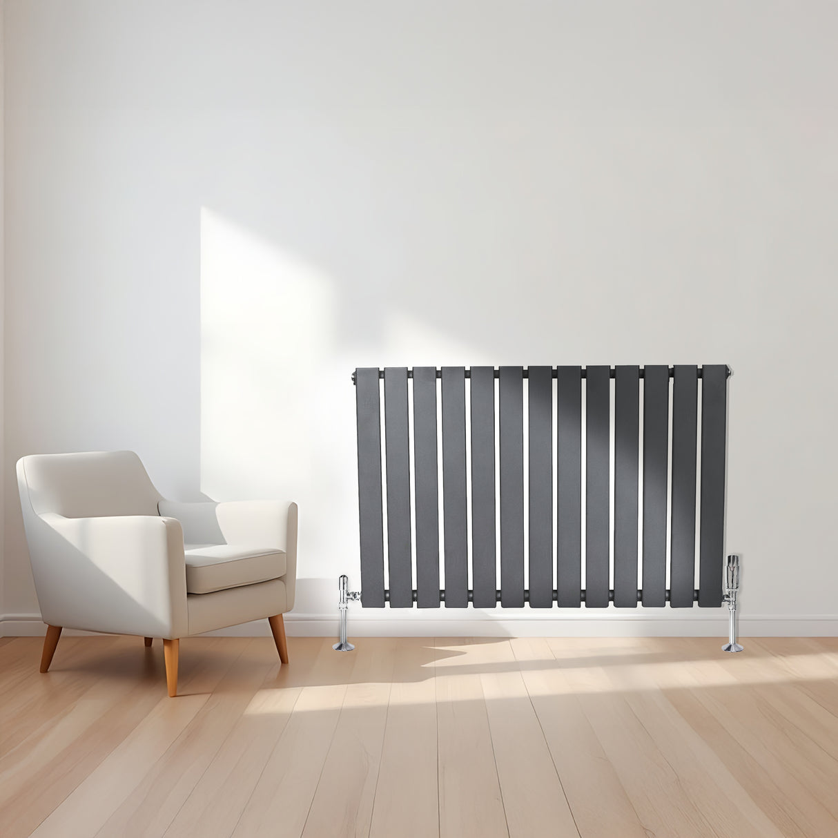 Radiatore piatto a colonna singola orizzontale antracite, con finitura liscia e linee moderne, posizionato accanto a una poltrona bianca su pavimento in legno chiaro