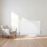 Radiatore piatto a colonna singola orizzontale bianco, con finitura liscia e linee moderne, posizionato accanto a una poltrona elegante
