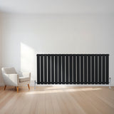 Radiatore piatto a colonna singola orizzontale nero, con design elegante e linee verticali, posizionato in un ambiente moderno con pavimento in legno chiaro