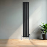 Radiatore verticale a colonna singola, 1600 x 280 mm, finitura nera opaca, con supporti cromati, in un ambiente moderno e luminoso
