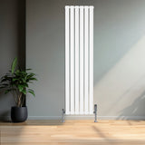 Radiatore verticale a colonna singola, bianco, con finitura liscia e linee moderne, posizionato in un ambiente minimalista con pianta verde