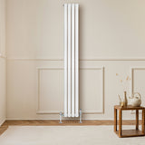 Radiatore ovale a colonna singola verticale bianco, elegante e moderno, posizionato su parete chiara, con pavimento in legno e arredo minimalista