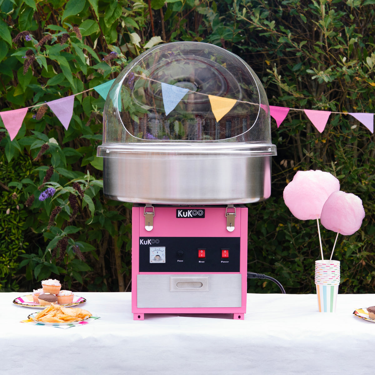 Macchina per zucchero filato Kukoo, con struttura rosa e acciaio inox, dotata di grande cupola trasparente e due pulsanti rossi, circondata da decorazioni colorate