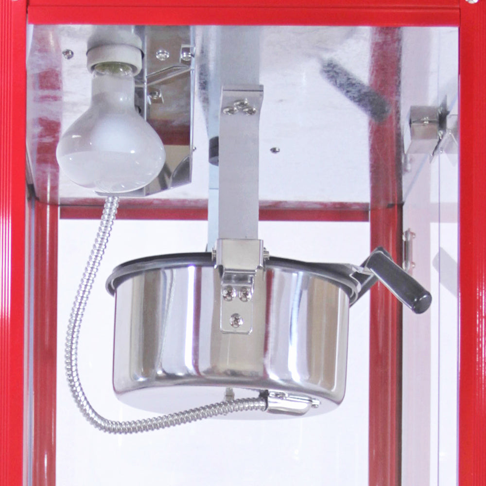 Macchina per popcorn con pentola in acciaio inox, lampadina sopra e manico laterale, struttura rossa e trasparente