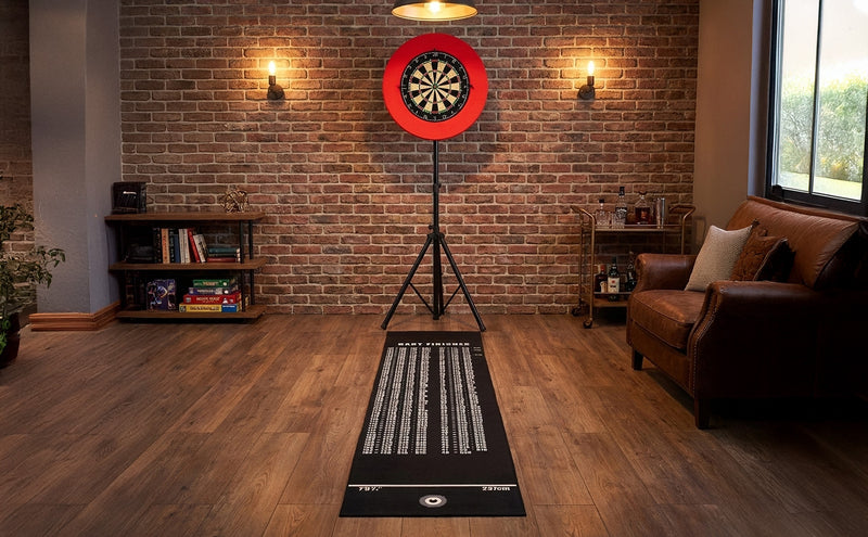 Tappeto da gioco nero con grafica bianca, posizionato in una stanza accogliente con pareti in mattoni e bersaglio per freccette rosso