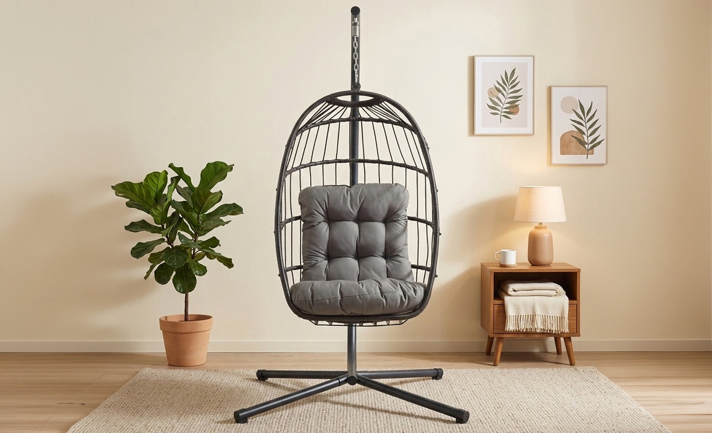 Sedia a sospensione nera con cuscino grigio, posizionata in un ambiente luminoso con piante e decorazioni minimaliste