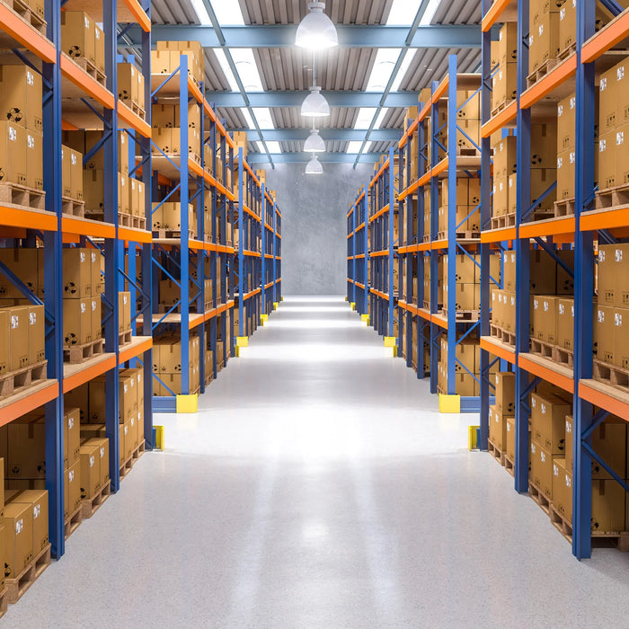 Magazzino ben organizzato con scaffali arancioni e blu, scatole di cartone marroni allineate, pavimento luminoso e illuminazione uniforme